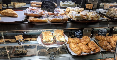 A display case filled with various pastries, including croissants, danishes, and blueberry cream cheese pastries.