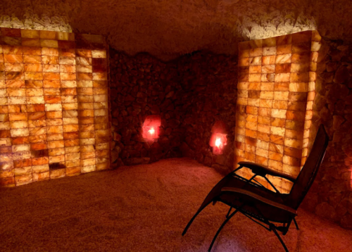 A tranquil salt room with illuminated salt walls and a reclining chair, creating a calming atmosphere.