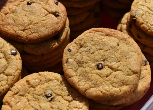 A close-up of freshly baked cookies with chocolate chips stacked in a bowl.