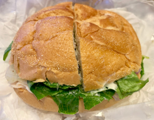 A freshly cut sandwich with lettuce and creamy dressing, served on a soft, golden-brown bun.