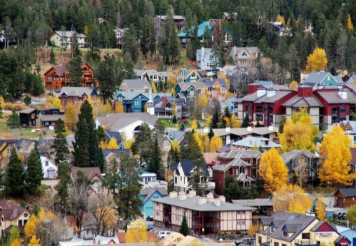 A scenic view of a colorful mountain town surrounded by trees and autumn foliage.
