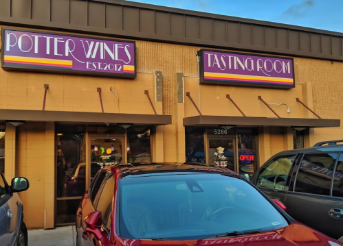Exterior of Potter Wines Tasting Room, featuring a sign with "Potter Wines" and "Tasting Room" above a parked car.