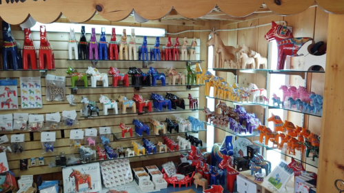 A colorful display of wooden animal figurines on shelves in a shop, featuring various sizes and designs.