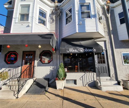 Exterior view of Mrs. Robino's restaurant, featuring a black awning and decorative elements on a sunny day.