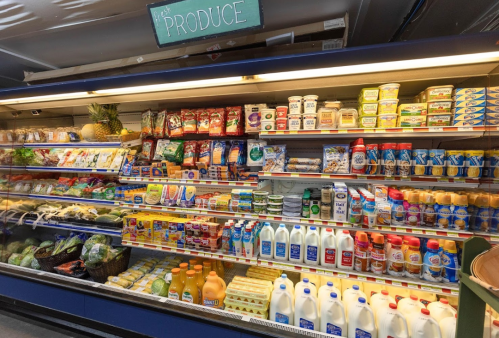A grocery store produce section filled with various fruits, vegetables, dairy products, and condiments on shelves.