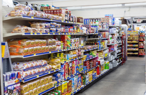 A grocery store aisle filled with various packaged foods, snacks, and beverages on shelves.