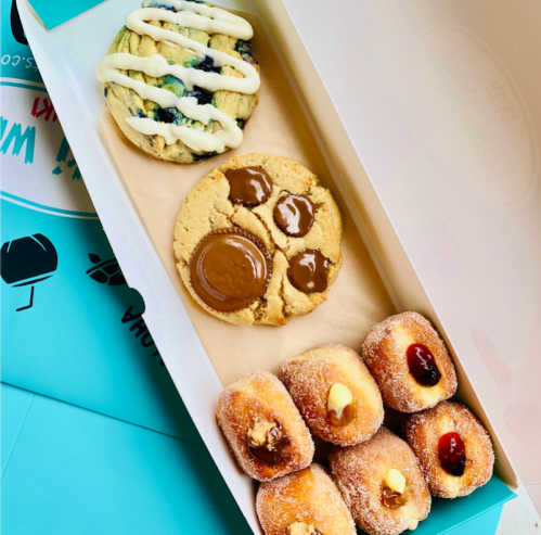 A box containing a cookie with icing, a cookie with chocolate, and assorted filled donuts.