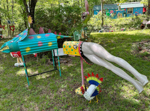 A whimsical garden scene featuring a colorful fish sculpture and a playful figure with sparkly legs diving into the grass.
