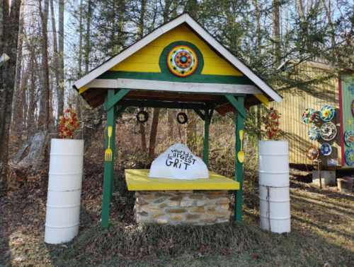 A colorful gazebo with a stone base and a large rock labeled "World's Largest Grit" surrounded by decorative elements.