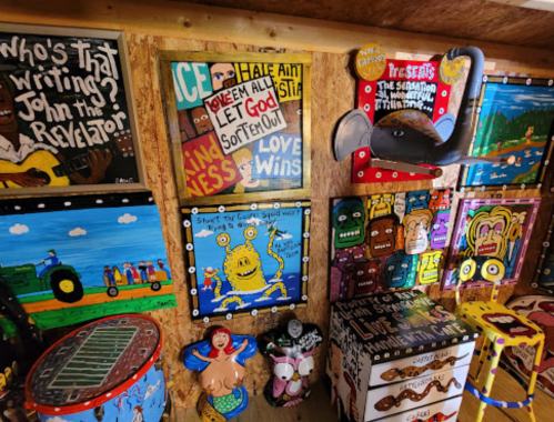 Colorful wall filled with eclectic artwork, including signs, paintings, and decorative objects in a vibrant, artistic space.