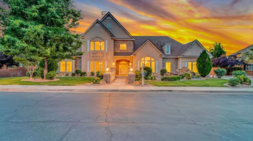 A beautiful house at sunset, featuring a landscaped yard and warm lighting from the windows.