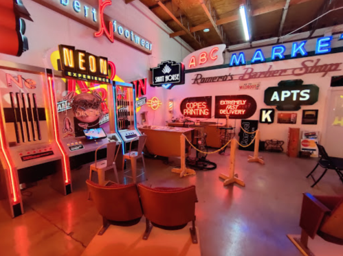 A vibrant room filled with vintage neon signs, arcade machines, and retro decor, creating a nostalgic atmosphere.