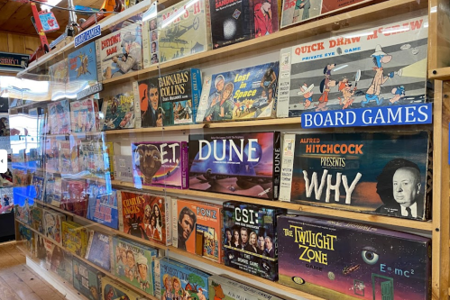 A display of various board games, including titles like E.T., Dune, and The Twilight Zone, in a wooden shop.