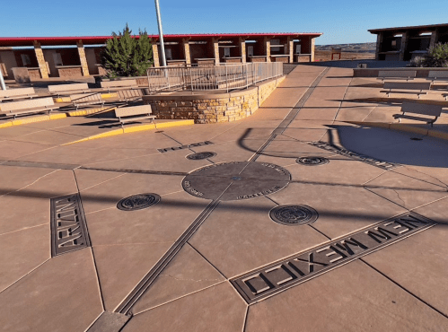 A circular plaza with engraved markers indicating directions to Arizona and New Mexico, surrounded by benches.