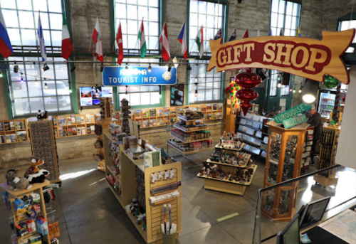 A vibrant gift shop filled with souvenirs, flags, and tourist information displays in a spacious, well-lit setting.