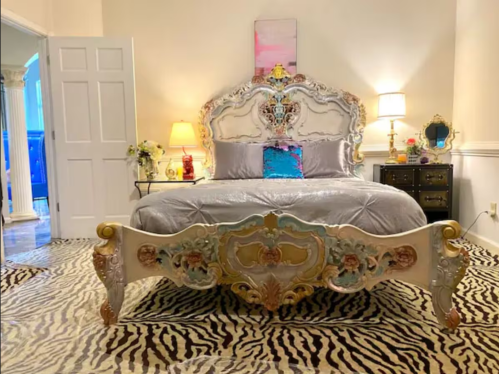 Luxurious bedroom featuring an ornate bed, elegant lamps, and a stylish zebra print rug.