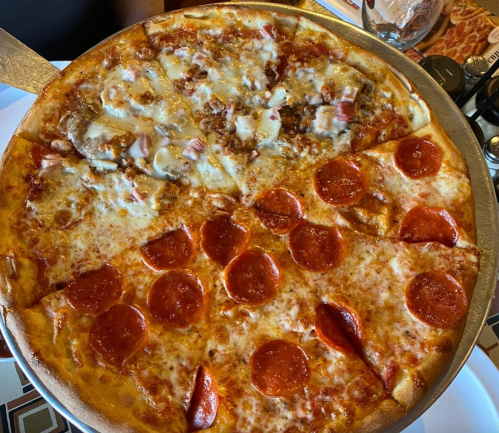 A large pizza divided into four sections: pepperoni, cheese, and two types of meat toppings.