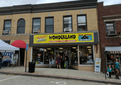 A storefront labeled "Wonderland Comics-Toys-Games" with people outside and a colorful sign.