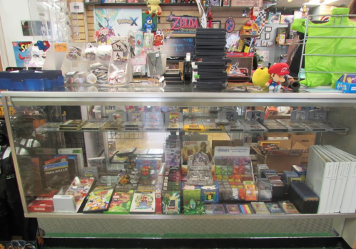 Display case filled with various video games, collectibles, and merchandise from popular franchises like Pokémon and Zelda.