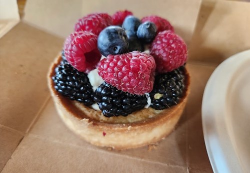 A delicious tart topped with fresh raspberries, blueberries, and blackberries on a golden crust.