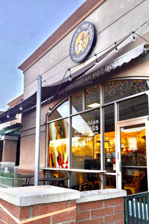 Exterior of Simón's Hot Dogs, a restaurant featuring Colombian hot dogs, with a welcoming storefront and outdoor seating.