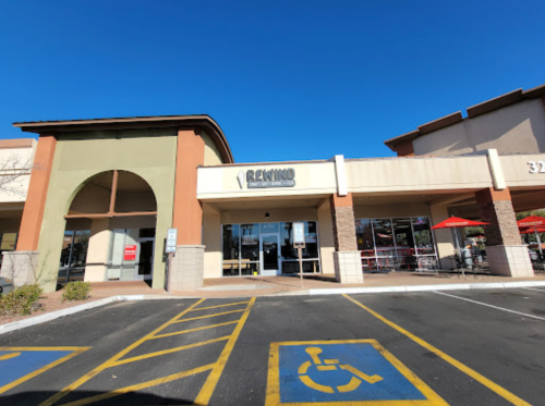 Exterior of a store named "Rewind," featuring a large entrance and outdoor seating under a clear blue sky.