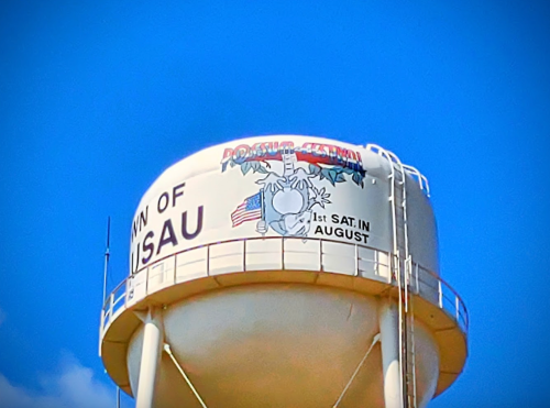 Water tower with "Town of Pahoa" and a graphic featuring a palm tree, American flag, and "1st Sat. in August" text.