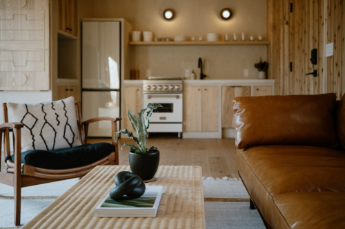 Cozy living space featuring a leather sofa, wooden accents, and a modern kitchen in the background.