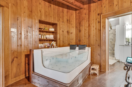 A cozy wooden bathroom featuring a large jacuzzi tub and shelves with toiletries.