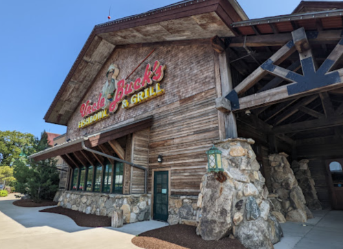 Exterior of a rustic wooden building with a stone base, featuring a sign for "Uncle Buck's Fish Bowl & Grill."