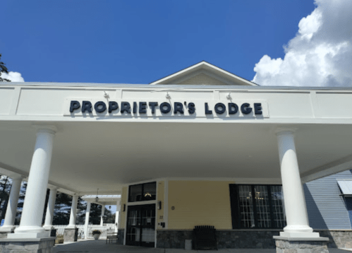 Exterior view of Proprietor's Lodge with a clear blue sky and white columns supporting the entrance.