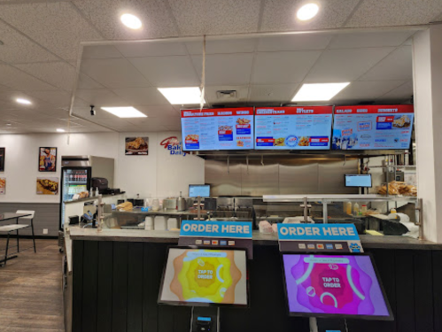 Interior of a fast-casual restaurant with digital menus and self-order kiosks. Bright and modern design.