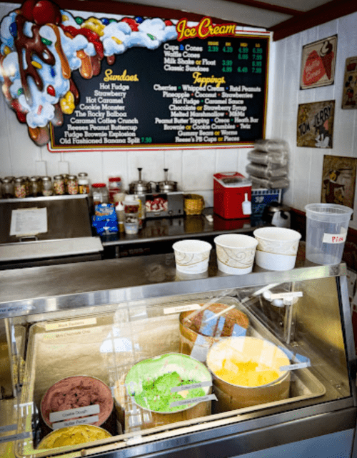 A colorful ice cream display with various flavors and a menu board in a cozy ice cream shop.