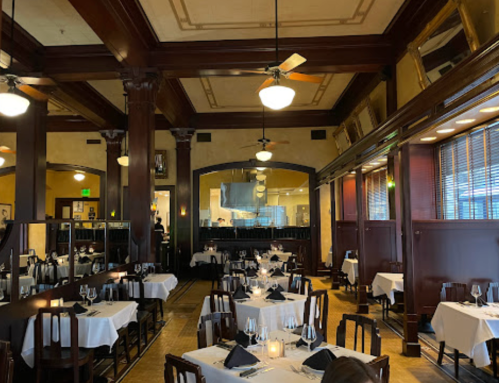 Elegant restaurant interior with wooden pillars, white tablecloths, and dim lighting, creating a cozy atmosphere.
