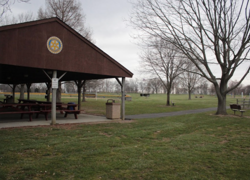 A park scene featuring a pavilion, picnic tables, and open grassy areas with bare trees in the background.
