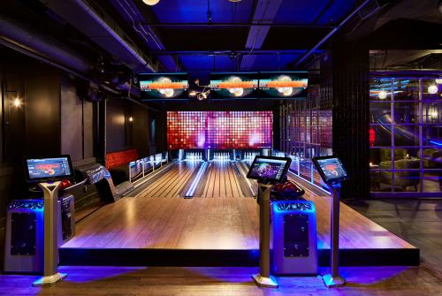 A modern bowling alley with vibrant lighting, digital screens, and sleek bowling lanes.