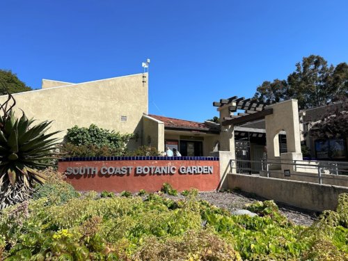Entrance to South Coast Botanic Garden with a clear blue sky and lush greenery in the foreground.