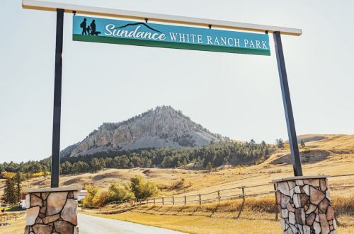 Sign for Sundance White Ranch Park with a mountain in the background and a clear blue sky.