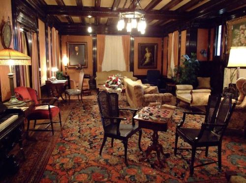 A cozy, vintage living room with elegant furniture, a patterned rug, and warm lighting, creating a welcoming atmosphere.