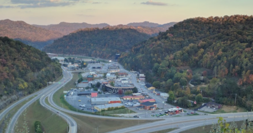 Aerial view of a small town nestled between mountains, with roads and buildings visible in the valley below.