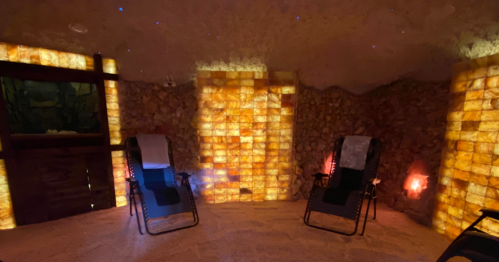 A tranquil spa room with salt wall panels, two reclining chairs, and soft lighting for relaxation.