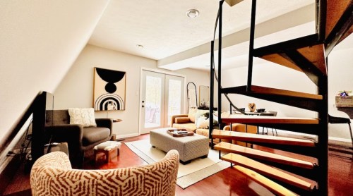 Cozy living space with modern furniture, a spiral staircase, and large windows letting in natural light.
