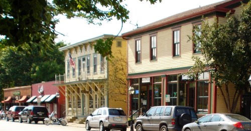 Charming street scene featuring colorful historic buildings and parked cars under a clear blue sky.