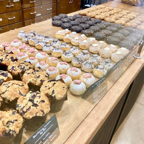 A display of various cookies and muffins in a bakery, featuring different flavors and toppings.