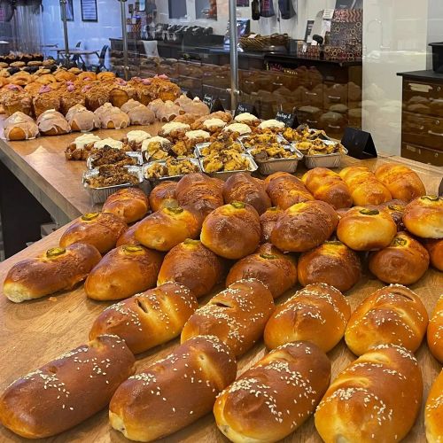 A bakery display featuring a variety of pastries, including buns and croissants, arranged on wooden counters.