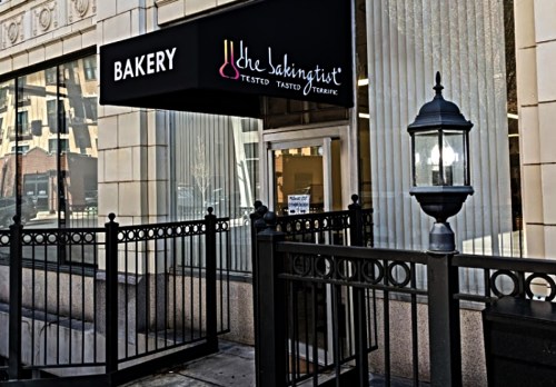Exterior of a bakery with a sign reading "the Bakingist" and a decorative lamp post nearby.