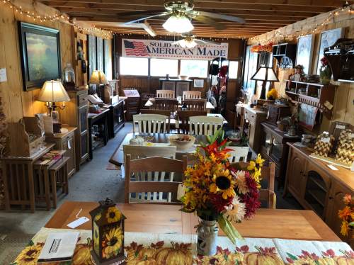 A cozy shop interior with wooden furniture, a flower centerpiece, and decor featuring an "American Made" banner.