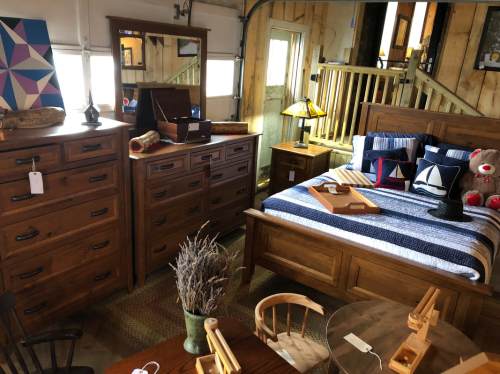 A cozy bedroom setup featuring a wooden bed, dresser, and various decorative items in a rustic interior.
