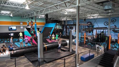 A vibrant indoor trampoline park with various attractions and people enjoying activities.
