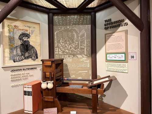 Display featuring a printing press, historical illustration of Gutenberg, and information about the invention of printing.